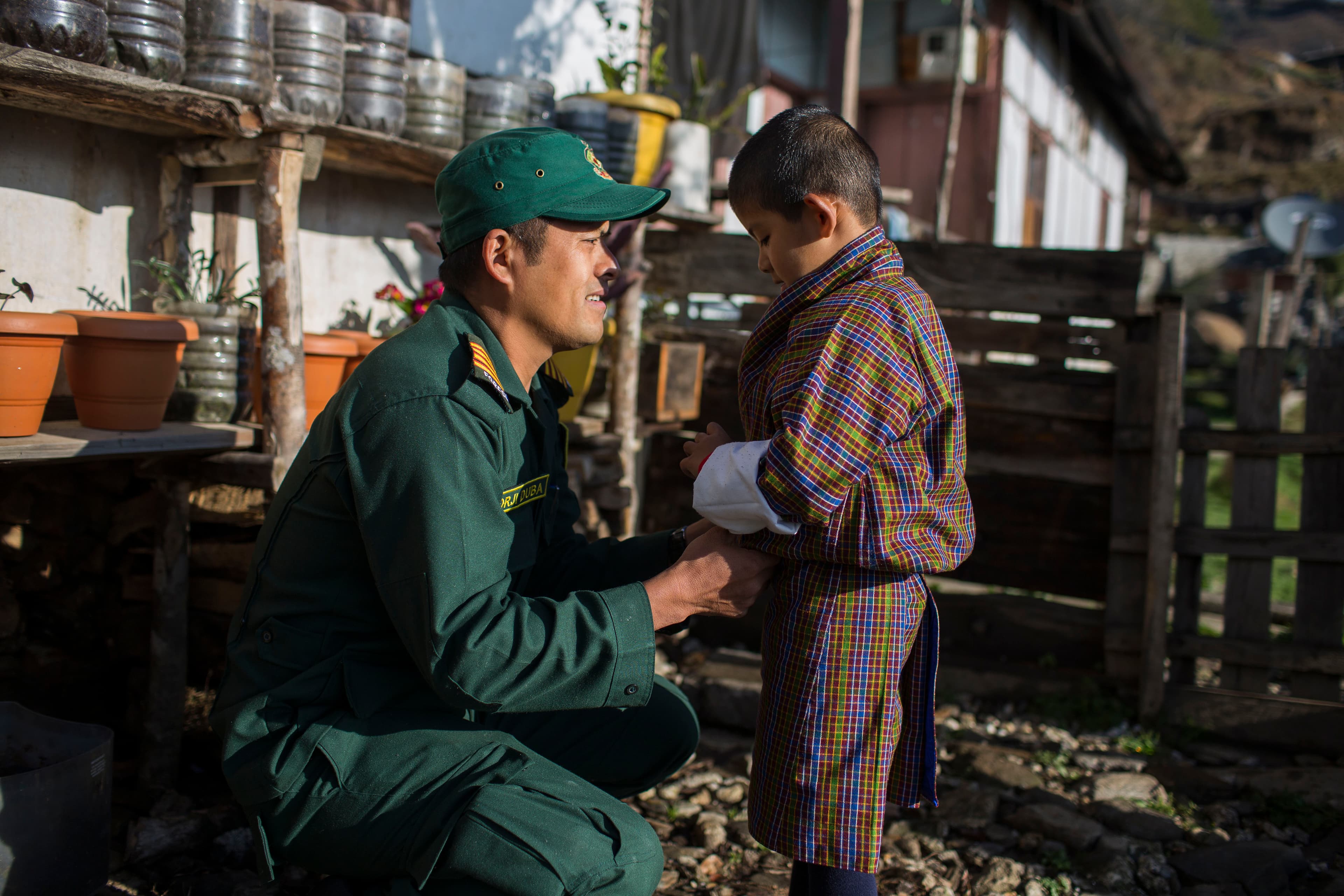 A ranger speaking with a child in a Bhutanese community setting.